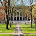 Media ‘Lynching’ Claim Ignites Cambridge Firestorm Students walking on a university campus with autumn trees and a historic building in the background