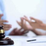Judge's gavel with wedding rings as two people argue in background