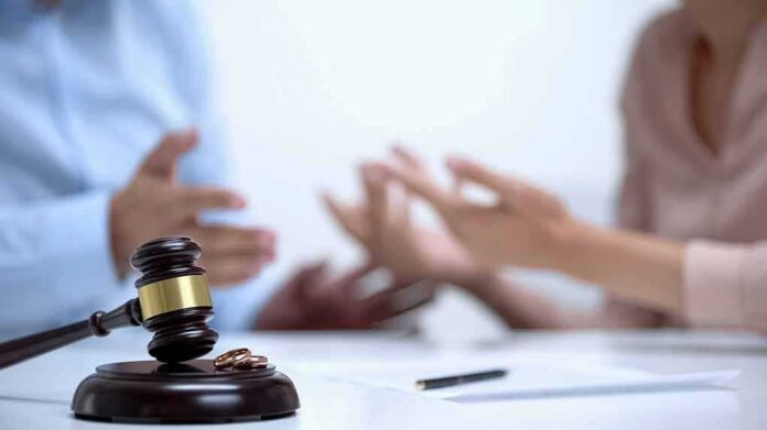 shutterstock_1539656573 Judge's gavel with wedding rings as two people argue in background