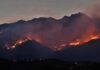 Wildfire burning along mountain slopes at dusk