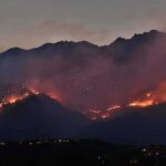Senators Target Fire Wagers — Why Now? Wildfire burning along mountain slopes at dusk