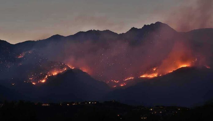 shutterstock_1762464629 Wildfire burning along mountain slopes at dusk