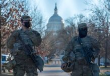 Guard Showdown Explodes in Washington Two soldiers stand guard with rifles on a city street