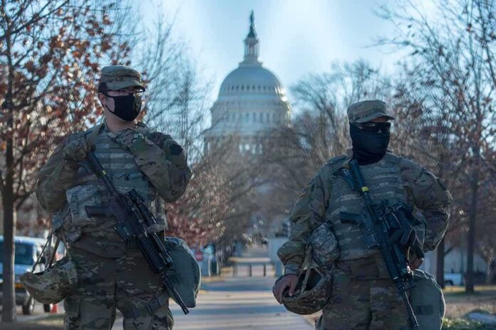 shutterstock_1898072065 Two soldiers stand guard with rifles on a city street