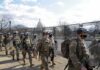 Billion-Dollar Bust? Guard Plan Under Fire Soldiers in riot gear patrol near a fenced government building
