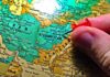 Hand placing a red pushpin on Afghanistan on a map