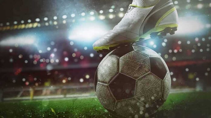 shutterstock_1927926020 soccer cleat on a ball under stadium lights