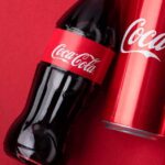 Coca-Cola Tool Glitch — Or Ideology Leak? Coca-Cola bottle and cans on red background