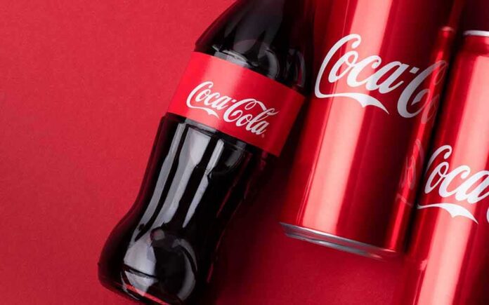 shutterstock_1939168312 Coca-Cola bottle and cans on red background