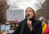 Hard-Left Mutiny: AOC Branded Moderate woman speaking into a microphone at an outdoor protest