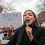 woman speaking into a microphone at an outdoor protest