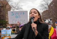 Hard-Left Mutiny: AOC Branded Moderate woman speaking into a microphone at an outdoor protest