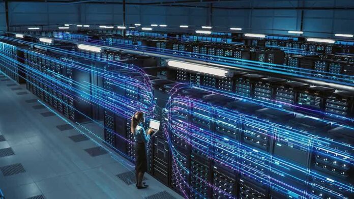 shutterstock_2204212039 Technician with laptop in a large data center aisle