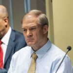 CNN Ambush Exposes Jordan’s “I Didn’t Know” Play Man in a light blue shirt and tie at a meeting table