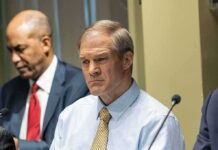 Man in a light blue shirt and tie at a meeting table