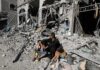Man with two children sitting amid rubble of a destroyed building