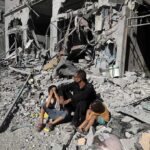 Water Collapse Sparks Gaza Health Fears Man with two children sitting amid rubble of a destroyed building
