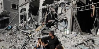 Man with two children sitting amid rubble of a destroyed building