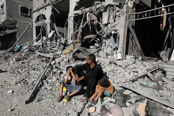 Man with two children sitting amid rubble of a destroyed building