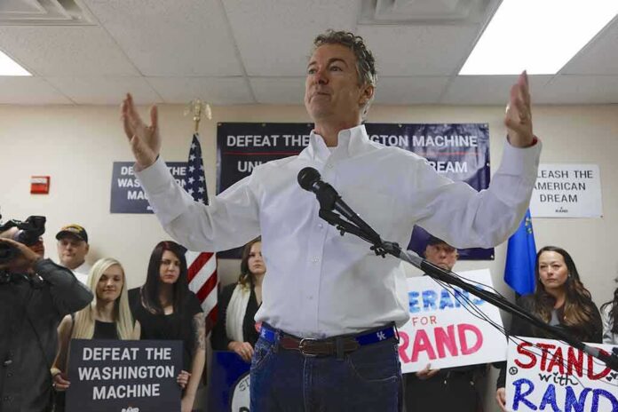 shutterstock_353101016 man in white shirt speaking at a rally with supporters and signs behind him