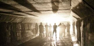 Silhouetted people standing in a concrete tunnel