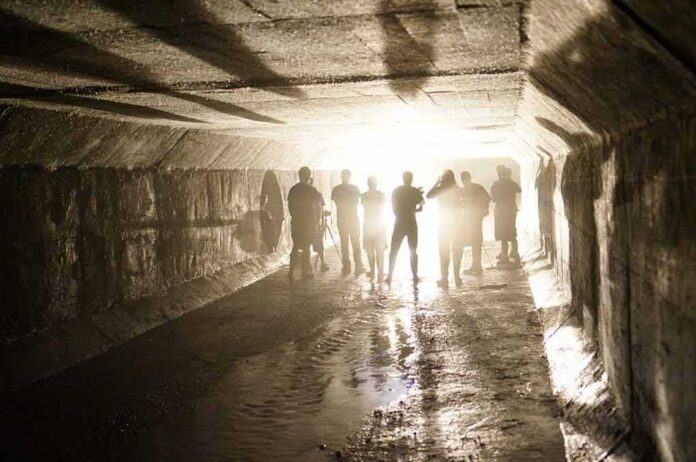 shutterstock_536260024 Silhouetted people standing in a concrete tunnel