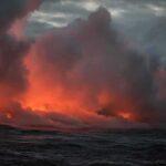 Volcanic steam plume over dark ocean at dusk