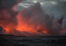 Volcanic steam plume over dark ocean at dusk