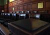 DOJ Pounces: ‘Spider’ Faces U.S. Justice Empty wooden jury box with numbered chairs