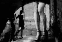 Moral Policing? Biometrics Target Adult Creators legs in high heels under an archway with blurred shadow figure
