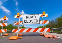 Road closed barricade with orange sandbags on a sunny day
