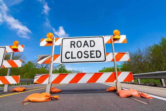 shutterstock_1388002637 Road closed barricade with orange sandbags on a sunny day