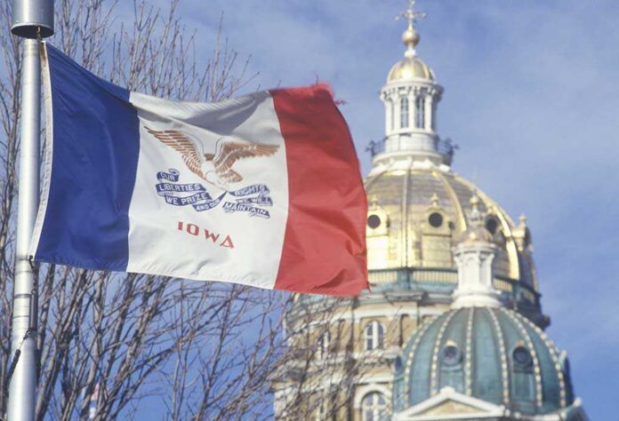 Iowa state flag waving in front of the state capitol building