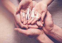 Hands holding a paper cutout family