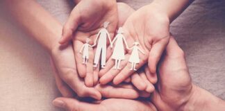 Hands holding a paper cutout family