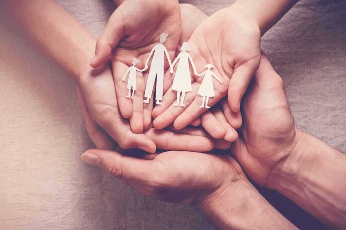 Hands holding a paper cutout family