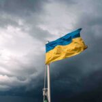 Patriot Drought Puts Kyiv In The Crosshairs Ukrainian flag waving against a stormy sky