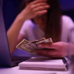Official Poverty Stat Misleads – By Design? Person counting cash beside a laptop