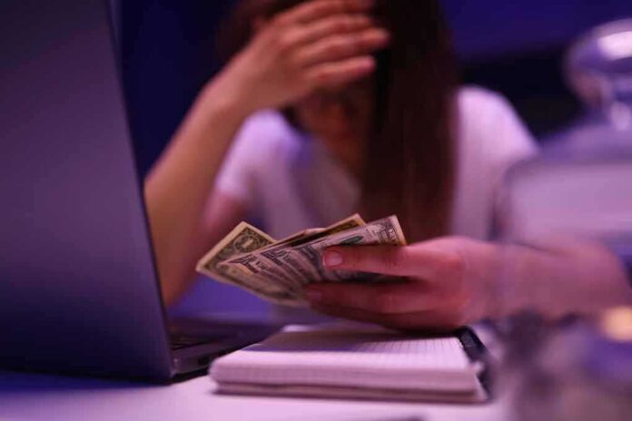 Person counting cash beside a laptop