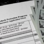 Paycheck Protection Program loan application with US hundred-dollar bills