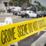 crime scene tape stretches across a blocked city street