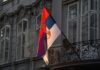 Term Limits Dodged – Leader Quits To Rule Anyway Serbian flag on a building facade