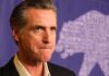 Newsom’s Radical Shift—Capitalism ‘Broken’ man in suit with serious expression