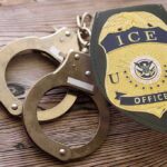Rushed ICE Hires, Now Sudden Purges ICE officer badge and handcuffs on wooden surface