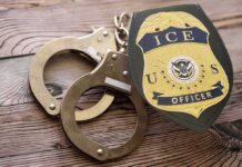 Rushed ICE Hires, Now Sudden Purges ICE officer badge and handcuffs on wooden surface