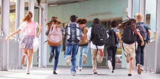 group of schoolchildren running with backpacks