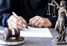Deportation Flights Axed – Criminal Offenders Stay? Judge writing at desk with gavel and Lady Justice statue