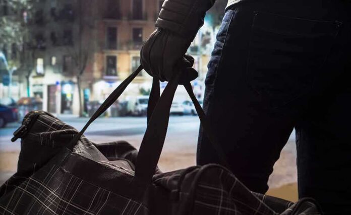 shutterstock_661803130 Person with gloved hand holding a duffel bag on a city street