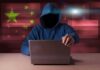 WeChat Clues Expose Covert Mission Hooded figure using a laptop with red cybersecurity graphics