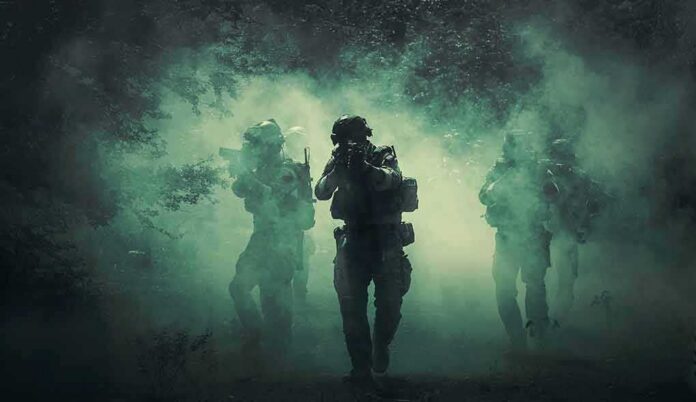 shutterstock_1045196350-1 Soldiers move through dense smoke in a forest